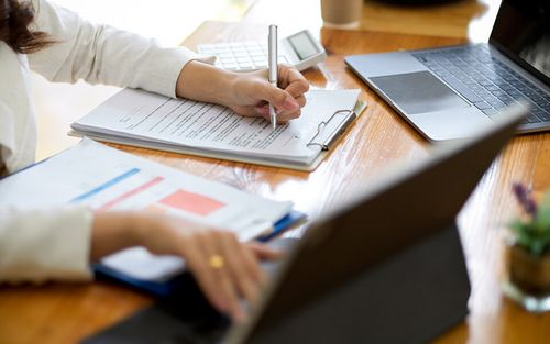 Frau bei der Arbeit am Tablet und beim Ausfüllen eines Formulars