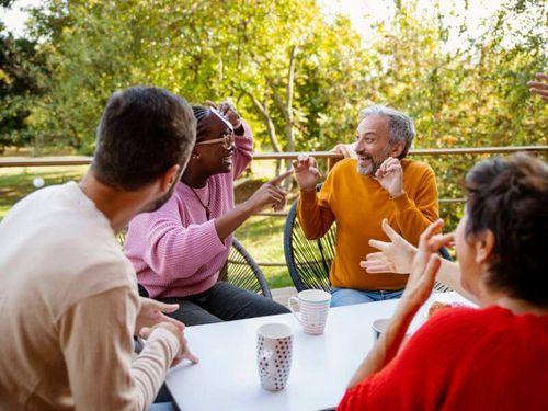Menschen sitzen zusammen am Tisch und lachen