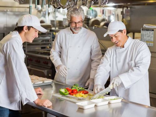 Drei Köche kochen in einer Großküche